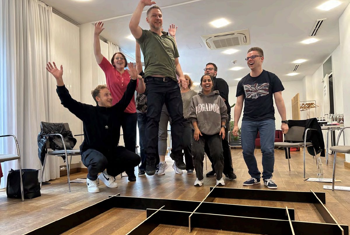 Team springt gemeinsam in die Luft während eines Workshops